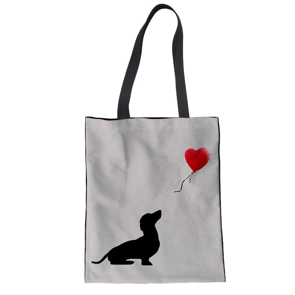 Tote bag with a black silhouette of a dog holding a red balloon on a white background similar to a Banksy design