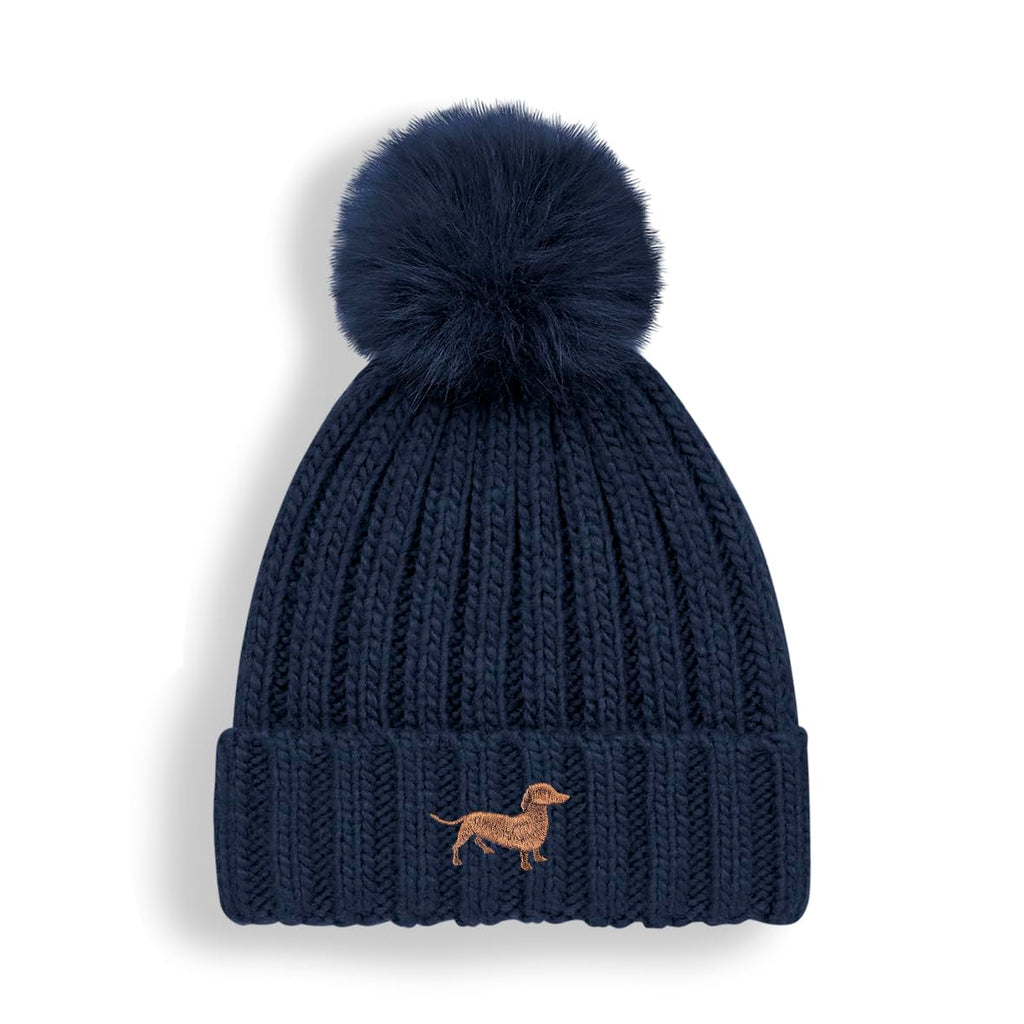 Navy blue knit beanie with pom-pom and dachshund embroidery on a white background